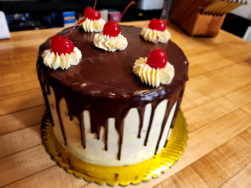 Cannoli Cake
Tender rum-soaked vanilla four layer
 cake nestled in between creamy sweet
 chocolate chip ricotta filling finished
 with an Italian butter cream frosting
 and a cascading chocolate drip.
 8" Serves 12-16